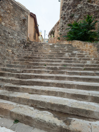 Old weathered stone stair between traditional worn stonewall building, Old Town of Chania Crete...