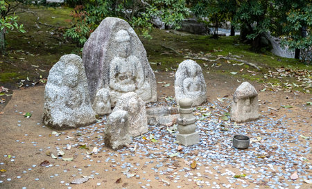 Small stone statues collection and coins on ground, Japanese garden. Shinto religion offerings
