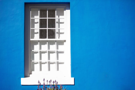White window on blue vibrant painted house wall, sunny day. South Africa. Bo-Kaap neighborhood in Cape Town,の写真素材