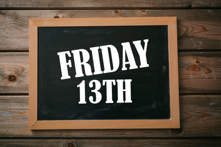 Friday the 13th text on a blackboard, wooden background. Bad luck date superstition, unlucky calendar dayの写真素材