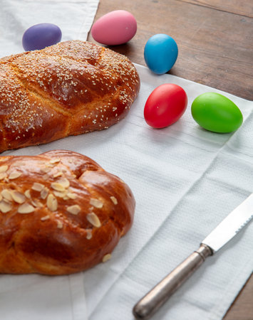 Easter sweet bread, two tsoureki braids and colorful Easter eggs on the table, above view