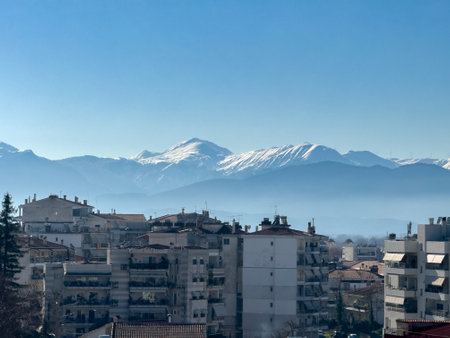 Trikala city, sunny winter day. Greece. Residential buildings and snow capped Pindus mountain background,の写真素材