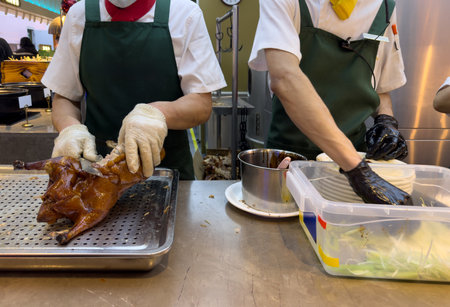 Peking duck preparation, Beijing restaurant, China. Chef carving meat with a sharp knife closeup on...