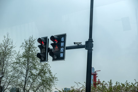 Traffic signal in China, two red traffic lights for cars, Right Turn Control text in chinese and a Surveillance Cameraの写真素材