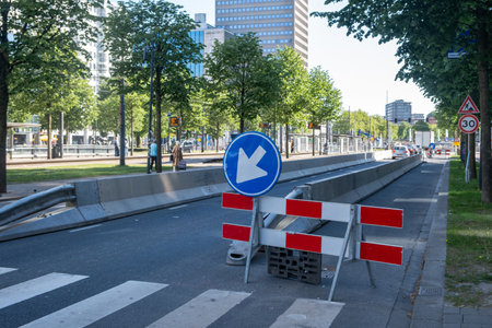 Road works in the city center, street lane closed with barricade, detour traffic signs and modern architecture buildingsの写真素材