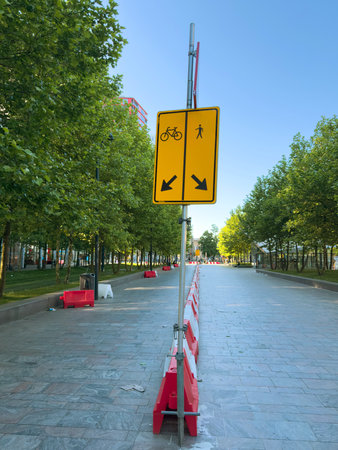 Traffic lanes temporary separation with red and white plastic barriers. Yellow sign arrows for bicycles and pedestrians.の写真素材
