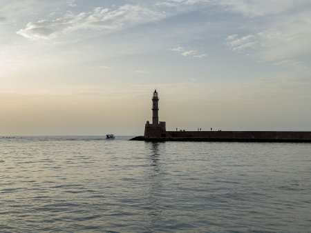 Chania Crete. Lighthouse at old venetian port, sunset sky with clouds and rippled seaの写真素材