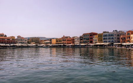 Chania old town cityscape. Traditional waterfront buildings and shops at old venetian harbour, sunny day, blue skyの写真素材
