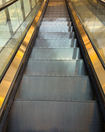 Empty escalators going down, luxury glass and golden finishings, shopping mall transitionの写真素材
