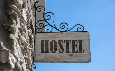 HOSTEL text sign, wooden sign on a building facade, blue slyの写真素材