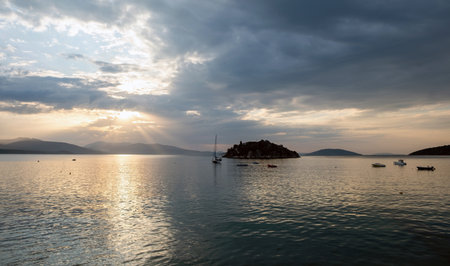 Serene sunset over Daskaleio rocky island in Tolo bay Greece. Boats moored on calm sea water under...