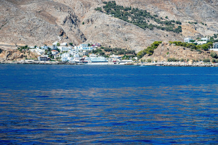 Coastal village of Sfakia on southern Crete island. Whitewashed houses by the deep blue sea, against rugged dry mountainsの写真素材