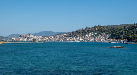 Poros Island panoramic view, Greece. Boats floating on calm blue water, traditional architecture...