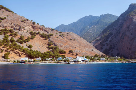 Agia Roumeli village at the base of steep rugged mountains along the southwest coast of Crete island, Greece. View from the boat approaching the villageの写真素材