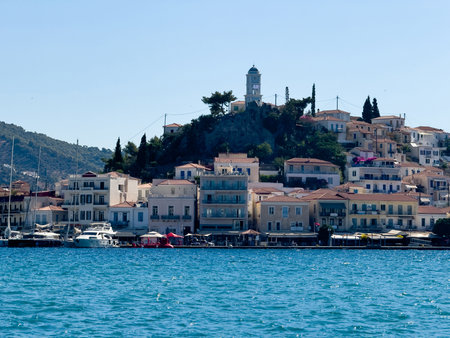 Waterfront view of Poros town Greece. The iconic clock tower on top of the hill, traditional architecture houses and moored boatsの写真素材