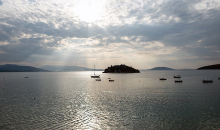 Serene sunset over Daskaleio rocky island in Tolo bay Greece. Boats moored on calm sea water under...