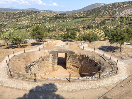 Ancient Tomb of Aegisthus at Mycenae, Greece, Mycenaean royal tholos tomb, beehive tomb. Olive groves and hills background, summer sunny dayの写真素材