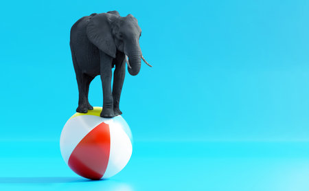 Elephant balancing on a colorful stripe beach ball on blue background, copy spaceの写真素材