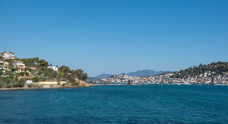 Poros Island panoramic view, Greece. Boats floating on calm blue water, traditional architecture...