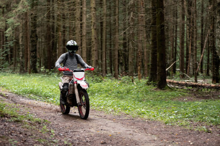 man in a helmet on a motorcycle rides on a forest dirt road