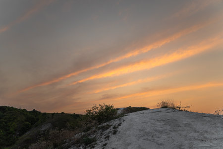 Top of hill under dark sky with feather pink clouds at sunsetの写真素材