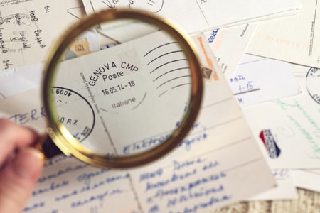 10 Jan 2022 Moscow, Russia -  Person looking through magnifier on postage stamp Poste italiane on postcardのeditorial素材