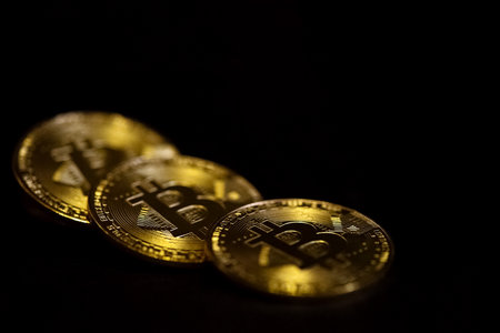 Three bitcoin cryptocurrency golden coins on black backgrouns