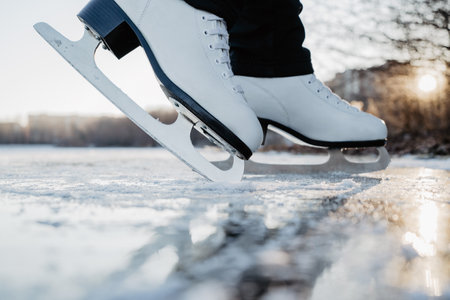 Woman wearing white fugure skates stands on frozen lake  ice. Winter outdoor sport activities