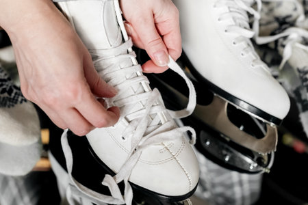 Woman hands tying laces on white ice skating bootsの写真素材