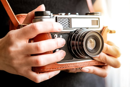Woman holds old vintage film slr photo camera in leather cover in her handの写真素材