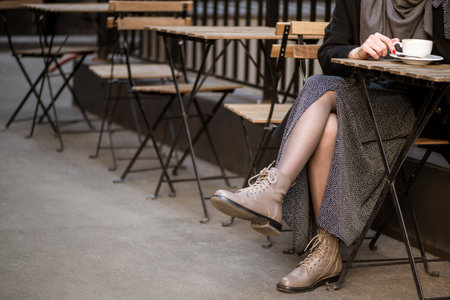 Woman sits in outdoor street cafe drinking coffeeの写真素材