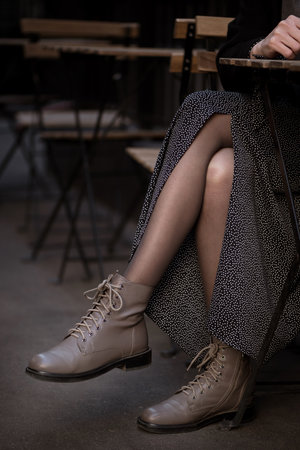 close up crossed legs of woman in leather boots sitting in street cafe
