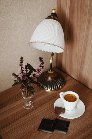 Small white cup of espresso coffee with bitten piece of chocolate on saucerの写真素材