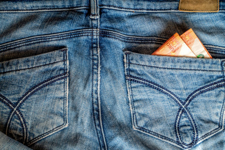 A few ten euro banknotes peeking out from back pocket of old blue jeans close upの写真素材