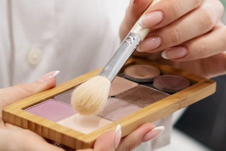woman holds nude makeup palette and brush in her handsの写真素材