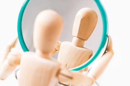 Wooden dummy looks at its reflection in the mirrorの写真素材