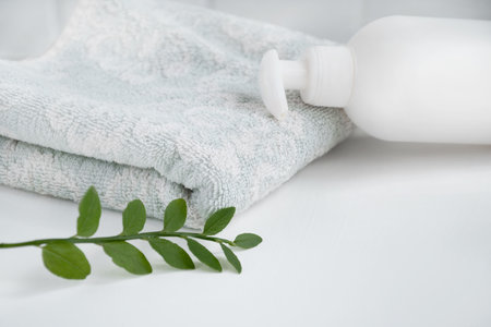 Cosmetic dispenser lays on fresh towel on bathroom toptableの写真素材