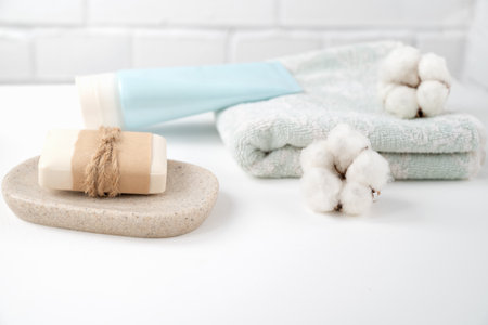 Bathroom table with new soap bar on tray and fresh clean towel decorated with fluffy cotton ballsの写真素材