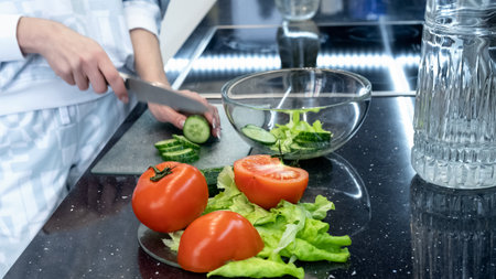 Process of preparing a vegetable salad. Slicing cucumbers and tomatoes. Healthy vegan eating and...