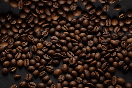 Scattered on surface dark roasted coffee beans background