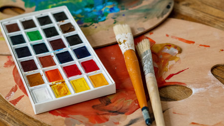 watercolor aquarelle palette and paintbrushes at painter artist wooden workplaceの写真素材