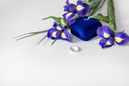 Valentine's day celebrate - bouquet of blue iris flowers and engagement ring laying in front od blue velvet gift boxの写真素材