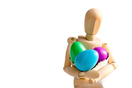 Wooden dummy holds colorful easter eggsの写真素材