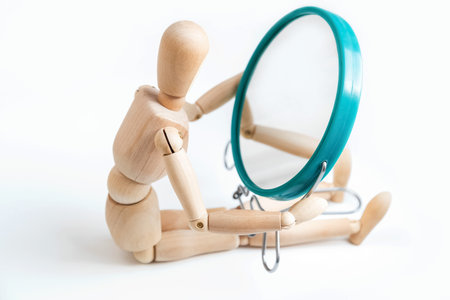 Wooden dummy looks at its reflection in the mirrorの写真素材