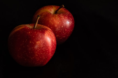 Two ripe fresh red apples with water drops on glossy peel on black backgroundの写真素材