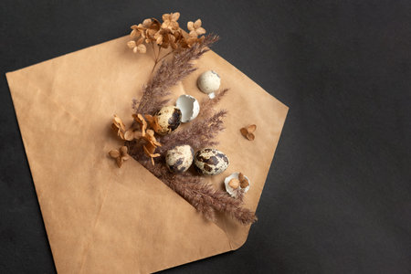 Happy easter composition with small eggs and dried flowers in craft paper envelope