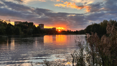sunset over calm lake in overcast eveningの写真素材