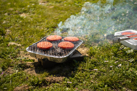 Grilling beef patties on a barbecue in the garden.の写真素材