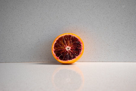 Sliced orange with red pulp, juicer in the backgroundの写真素材