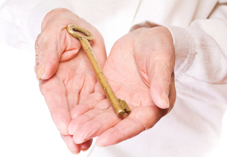 Old woman holding a key in her hands, with white backgroundの写真素材